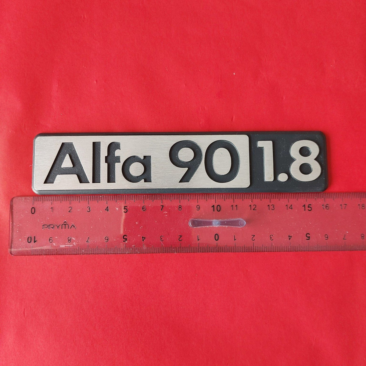 Targhetta Alfa Romeo 90 1.8 NOS con righello per riferimento dimensionale
